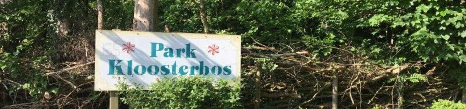 Bomen en een bordje waar op staat 'park Kloosterbos'